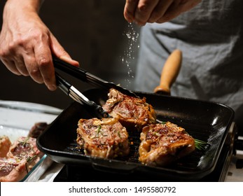 Chef hands cooking lamb steak meat on hot grill pan on kitchen black background. - Powered by Shutterstock