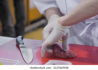 Chef hands holding knife and preparing minced meat burger cutlet on red cutting board - close up. Professional cooking, cookery, gastronomy and food concept - Powered by Shutterstock