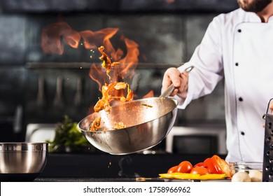 Chef hands keep wok with fire. Closeup chef hands cook food with fire. Chef man burn food at professional kitchen. - Shutterstock ID 1758966962