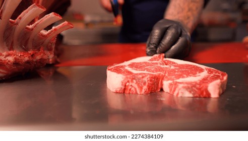 Chef hands making a heart shape form raw fresh beef meat ribeye. Juicy fresh meat steak on board with different meat goods around. - Powered by Shutterstock