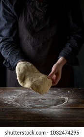 Chef hands preparing dough for italian pizza, pasta or bread preparation over wooden background, top view, flat lay