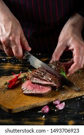 Chef Hands Slicing Beef Steak With Knife On Wood Cutting Desk. Top View Food Preparation Process Concept.