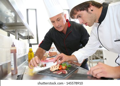 Chef helping student in catering to prepare foie gras dish - Powered by Shutterstock