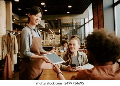 Chef holding digital menu beaming at diverse group of young customers in modern, stylish cafe with brick walls and large windows creating cozy atmosphere - Powered by Shutterstock