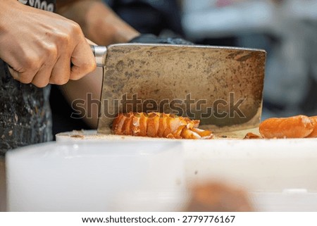 Chef holding kitchen knife cutting grilled sausage