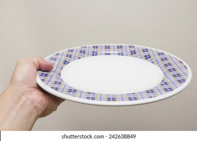 Chef holds empty  white plate, it is beautiful stripes pattern on cream background