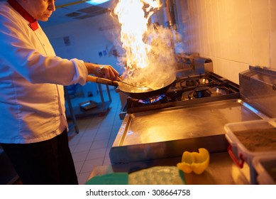 Chef In Hotel Kitchen Prepare Vegetable  Food With Fire