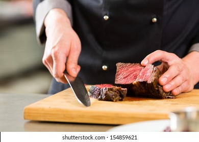 Chef In Hotel Or Restaurant Kitchen Cooking, Only Hands, He Is Cutting Meat Or Steak