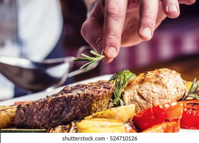 Chef in hotel or restaurant kitchen cooking only hands. Prepared beef steak with vegetable decoration. 