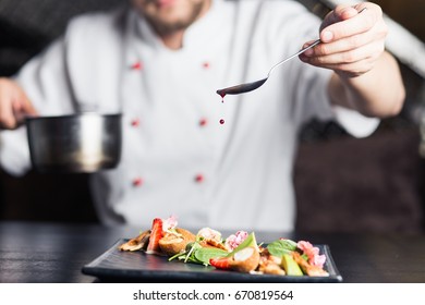 Chef in hotel or restaurant kitchen cooking, only hands. He is working on the micro herb decoration - Shutterstock ID 670819564