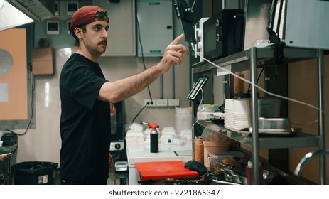 Chef interacting with a digital tablet and microwave in a ghost kitchen, preparing food