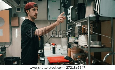 Chef interacting with a digital tablet and microwave in a ghost kitchen, preparing food
