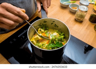 Chef at the kitchen preparing green curry with herbs and rice