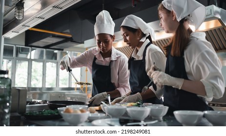 Chef in the kitchen provides cooking training to students.Schoolgirls happily cook together.children wearing cooking uniform. - Shutterstock ID 2198249081