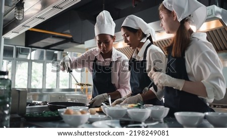Chef in the kitchen provides cooking training to students.Schoolgirls happily cook together.children wearing cooking uniform.