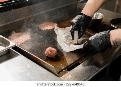 The chef in kitchen of the restaurant makes cutlets for burgers - smash burger beefsteak