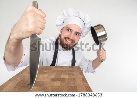 Chef knife. Cook is showing off his knife. Satisfied cook with pan in his hands. Cutting board. Concept - sale of knives for chefs. Chef recommended knive. Inventory for restaurant's kitchen. Cafe