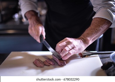 chef with knife and cutting tasty grilled steak