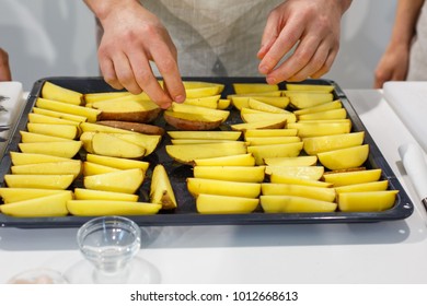 Chef Lays Potato Wedges With Spices In Baking Dish. Family Dinner On Holidays. Cooking In Cozy Kitchen At Home