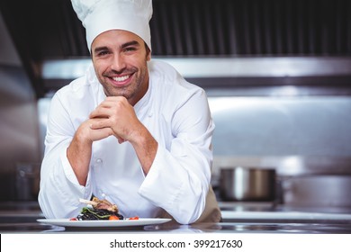 Chef leaning on the counter with a dish in a commercial kitchen - Powered by Shutterstock