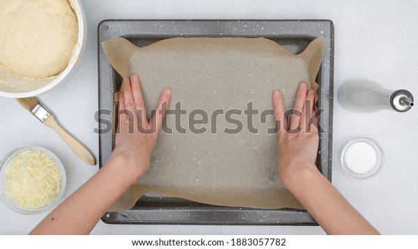 Chef\
lines baking pan with parchment paper. Cheese bread step by step\
recipe. Baking process, close up view from\
above