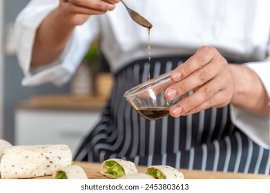 chef make tortilla wrap vegetable salad slice by knife on cutting board and mix sour salad dressing in small bowl glass with wine and olive oil. tortillas wrap vegetable and juicy liquid sour dressing - Powered by Shutterstock