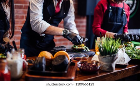 Chef Making Beef Burgers Indoor At Restaurant Kitchen, Participating In Food Festival Event.