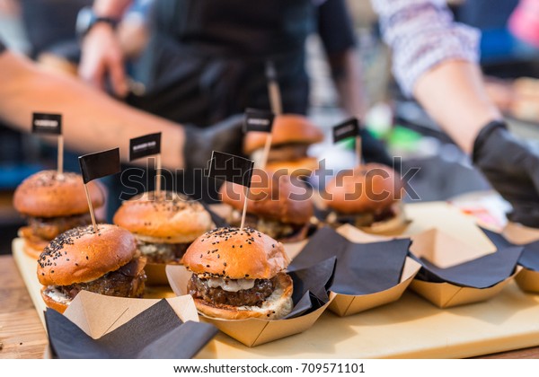 Chef making beef burgers outdoor on open kitchen\
international food festival event. Street food ready to serve on a\
food stall.