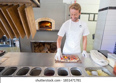 Chef Making Pizza In The Kitchen Of A Restaurant