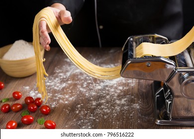 Chef making spaghetti noodles with pasta machine on kitchen table with some ingredients around.
 - Powered by Shutterstock