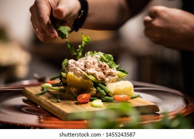 Chef Making Tuna Salad In Hot Potato With Tomato, Eggs And Herbs On Wooden Cutting Board