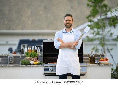 chef man at barbecue and grill hold utensil, copy space. chef man at barbecue and grill outdoor. - Shutterstock ID 2303097367