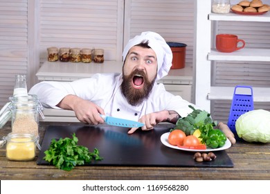 Chef man. Kitchen accessories, cooking equipment. Male chef cutting his finger. Bearded man cut in his finger with knife. Crazy cook in white uniform cuts finger with knife. Preparing meal in kitchen.