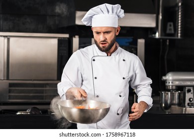 Chef Man Prepare Food At Kitchen Restaurant. Serious Chef Tossing Asian Food. Chef Male With Wok Prepare Spicy Meal At Professional Kitchen.