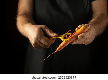 A chef peels carrots with a knife. Preparing to cook a dietary vegetable dish in a tavern kitchen. Advertising space. - Powered by Shutterstock