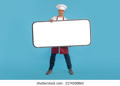 Chef Phone. Big Phone In Hands Of Chef. Satisfied Restaurant Chef Shows Cellphone. Man In Uniform Of Restaurant Employee. Smartphone Mockup With Place For Text. Space For Apps In Cellphone