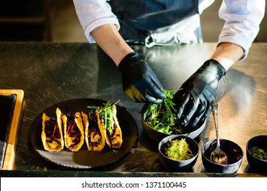 A Chef Plating Tacos In A Kitchen