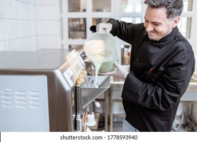 Chef Pouring Mixed Milk Base Into The Ice Cream Machine Or Freezer At The Small Ice Cream Manufacturing Or Restaurant Kitchen