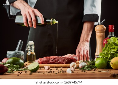 Chef pouring olive oil onto raw meat. Seasoning beef steak with pepper, salt, garlic, lime and lemon juice. - Powered by Shutterstock