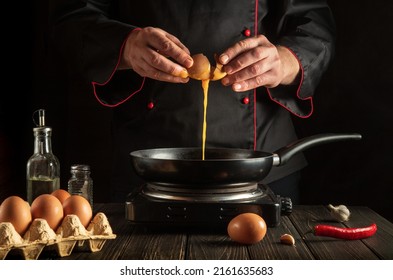 Chef pours a raw egg into a frying pan. Delicious breakfast menu idea for a hotel or restaurant - Powered by Shutterstock