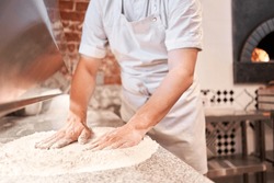 The Chef Prepare Pizza. Raw Pizza Ready To Bake. Cook In A Apron In The Kitchen Rolls Out Pizza Dough. Boxes For Food Delivery On Background.