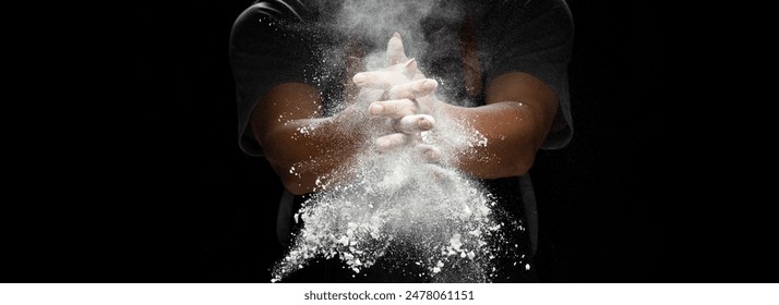 Chef prepare white flour dust for cooking bakery food. Elderly man Chef clap hand, white flour dust explode fly in air. Flour stop motion in air with freeze high speed shutter, black background