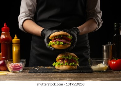 the chef prepares a burger, a hamburger. on a background with ingredients. Delicious and fast food, fast food. A menu, a cafe, fast food, catering, gastronomy - Powered by Shutterstock