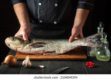 The chef prepares carp fish. Preparation for cooking fish food. Working environment in the restaurant kitchen - Powered by Shutterstock