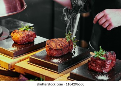 The Chef Prepares Fillet Of Mignon. Mignon On A Black Plate In The Restaurant. Close Up