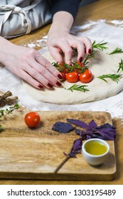 The chef prepares Focaccia, lays tomatoes on the dough. side view, wooden background - Shutterstock ID 1303195489