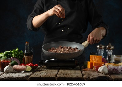 Chef prepares meat in pan wok for cooking traditional mexican tacos. Dark background. Frozen motion. Food concept. Ingredients for dish on the rustic wooden table. - Powered by Shutterstock