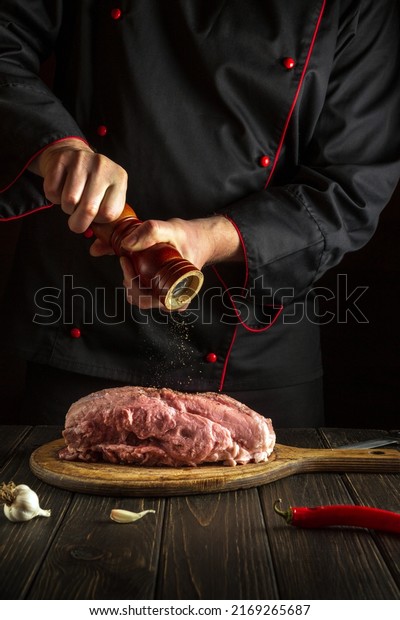 The chef prepares raw veal meat. Before baking,\
the cook adds pepper to the beef. National dish is being prepared\
in the kitchen