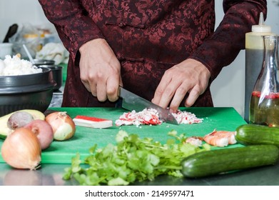 chef prepares a salad of crab sticks, cucumbers, corn eggs in the kitchen. Man cutting crab sticks for salad - Shutterstock ID 2149597471