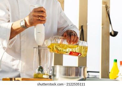 The chef prepares the sauce by adding olive oil and blending it with an immersion blender. Recipe for natural mustard and various spices. Close-up. unrecognizable person